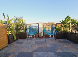 Terrazzo con giardino tropicale e sedie blu, ideale per consulenze giardinaggio e progettazione verde.