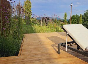 Giardino privato con flora mediterranea e sedie a sdraio su pavimento in legno Giardino privato con flora mediterranea e sedie a sdraio su pavimento in legno