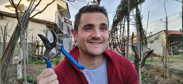 Giardiniere sorridente con cesoie in mano in un orto