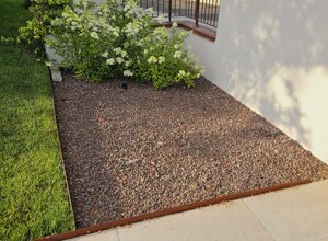 Giardino con area verde e aiuola con ghiaia e fiori bianchi Giardino con area verde e aiuola con ghiaia e fiori bianchi