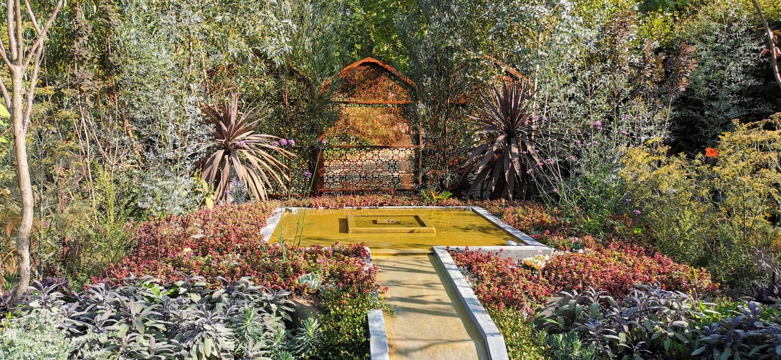 Giardino con design sostenibile, con piante e fontana centrale.