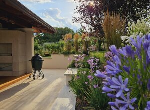Giardino privato con fiori viola e barbecue, verde a sfioro Giardino privato con fiori viola e barbecue, verde a sfioro