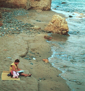 Seduta sulla spiaggia a disegnare il mare