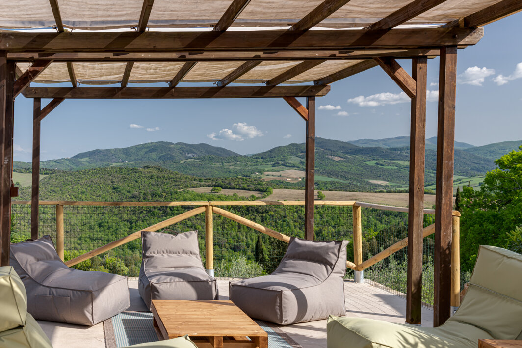 Sun loungers and relaxation chairs next to the panoramic swimming pool in Tuscany