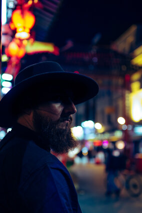 MURDAH SRVC artist profile shot with blurred red Chinese lanterns - cinematic night photography in London