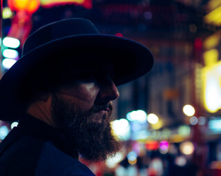 MURDAH SRVC artist profile shot with blurred red Chinese lanterns - cinematic night photography in London