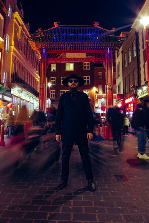 Bearded man with hat and sunglasses standing in a busy city street at night murdah srvc photo