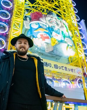 MURDAH SRVC artist wearing a black hat in Dotonbori Osaka - Japanese pop culture inspired music project
