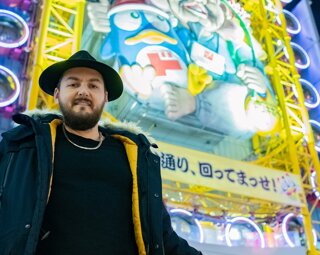MURDAH SRVC artist wearing a black hat in Dotonbori Osaka - Japanese pop culture inspired music project