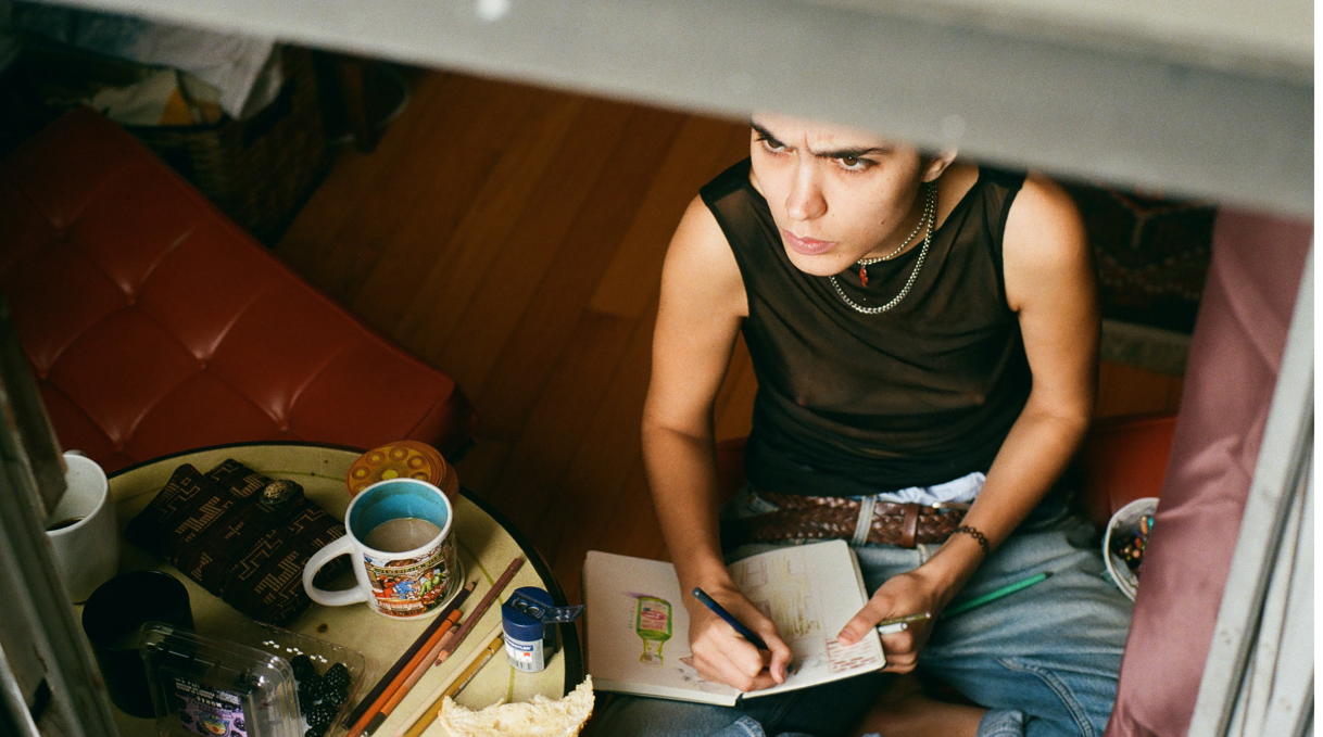 Artist working in sketchbook at studio desk, overhead photo
