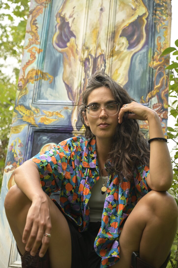 eyJlbiI6IlZhbGVudGluZSBBbG1hIHBvcnRyYWl0IGluIE1vbnRy6WFsLCBRdeliZWMsIHNlYXRlZCBvdXRkb29ycyBpbiBmcm9udCBvZiBwYWludGVkIGFydHdvcmsuIn0=