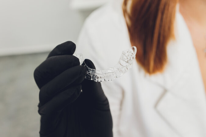 close-up-woman-s-hand-putting-transparent-aligner-teeth.jpeg