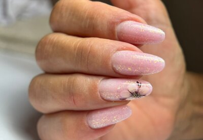 unghie ricostruite con smalto glitter rosa e disegno fiorito esaltano la forma della mano di donne