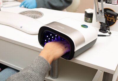 cliente mette la mano nel fornetto per la ricostruzione unghie