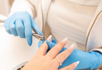 estetista esegue una manicure togliendo le pellicine dalle mani della cliente