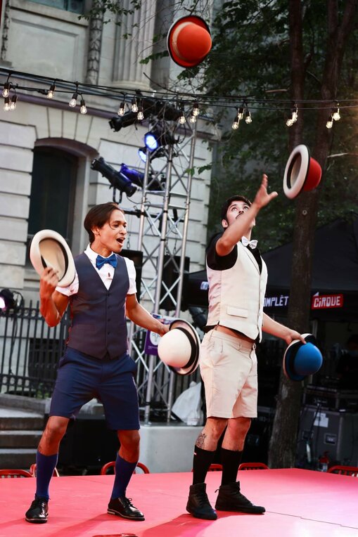 Deux jongleurs en train de lancer des chapeaux lors d'un spectacle de rue en plein air Deux jongleurs en train de lancer des chapeaux lors d'un spectacle de rue en plein air