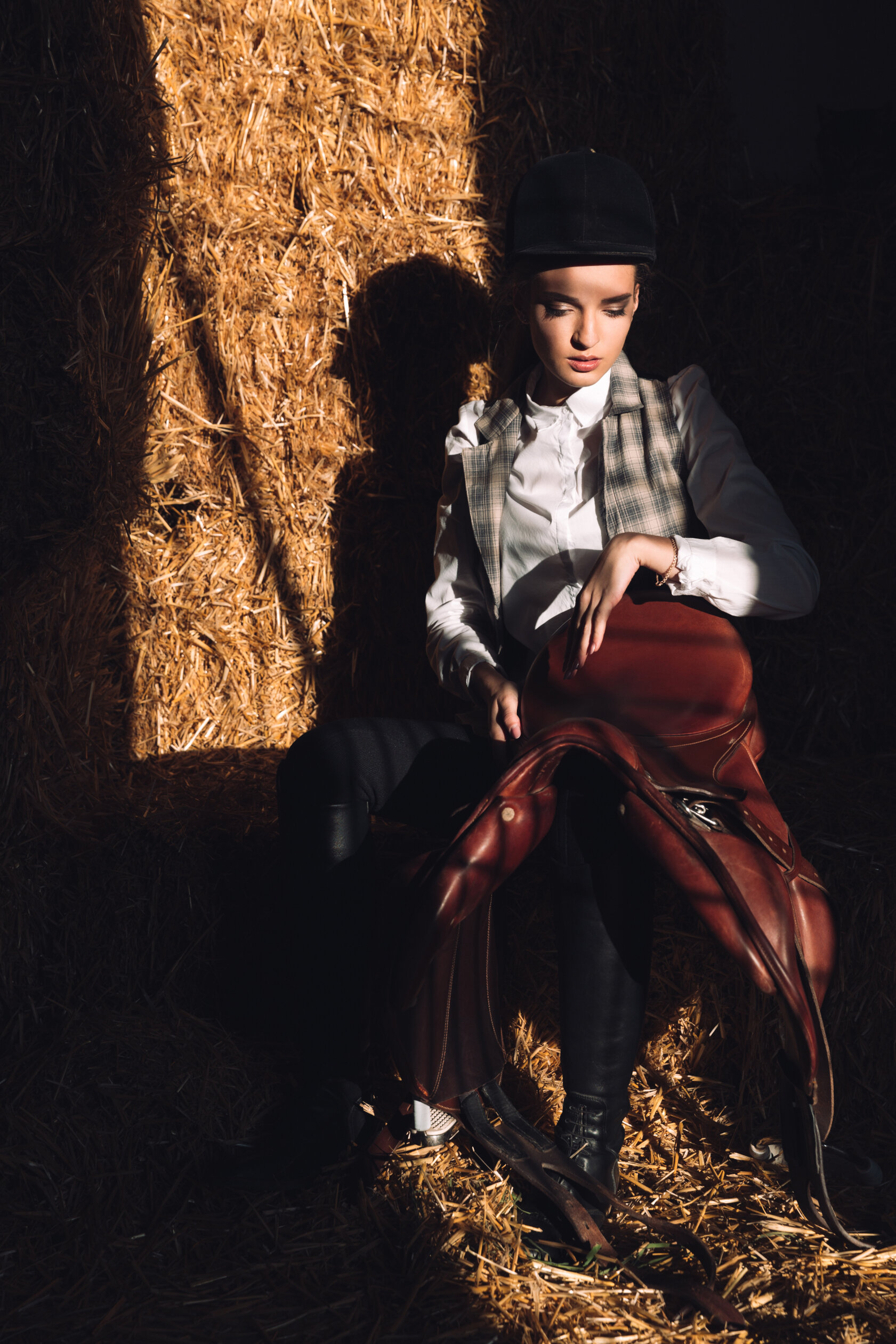 serious-young-woman-sitting-barn-with-seddle.jpeg