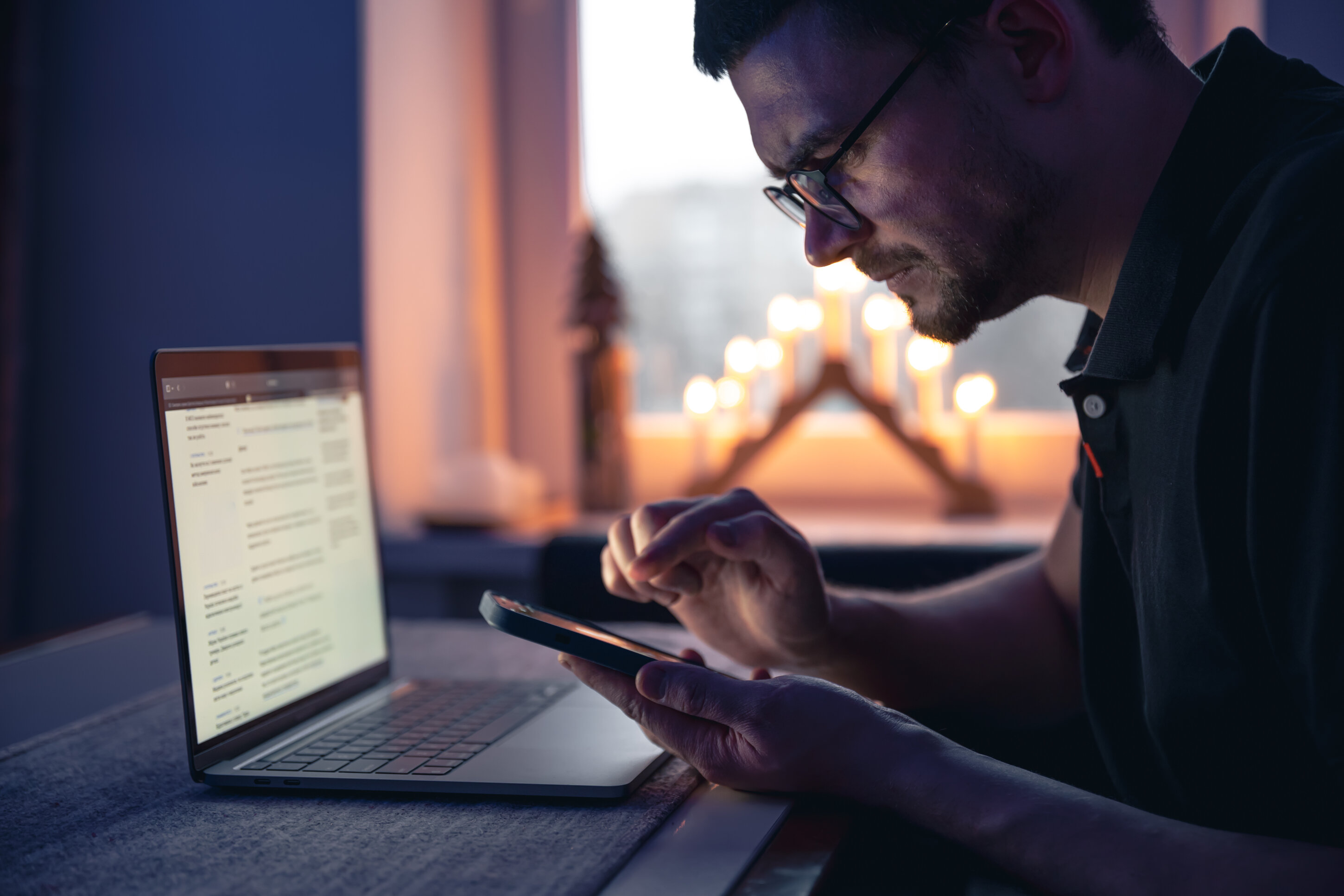 man-with-smartphone-sits-front-laptop-late-night.jpeg