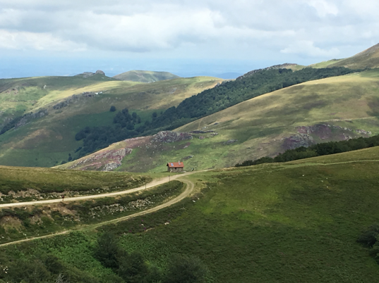 Paesaggio montano con una piccola casa in mezzo a colline verdi Paesaggio montano con una piccola casa in mezzo a colline verdi