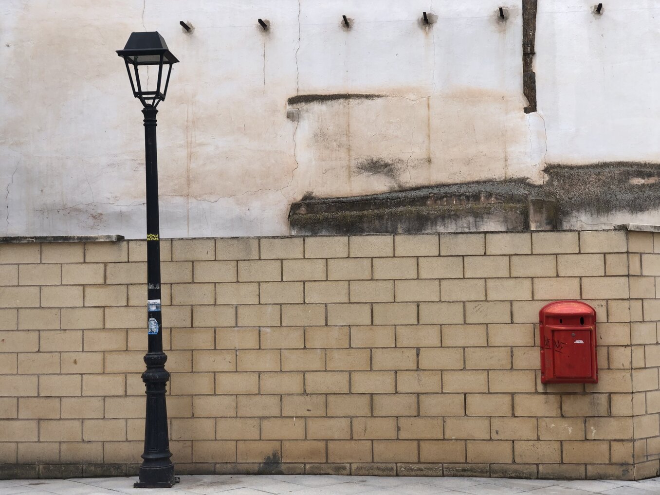 Lampione e cassetta postale su un muro di mattoni